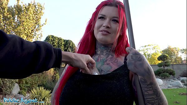 Hot redhead agent flaunts big boobes & inked arms for work
